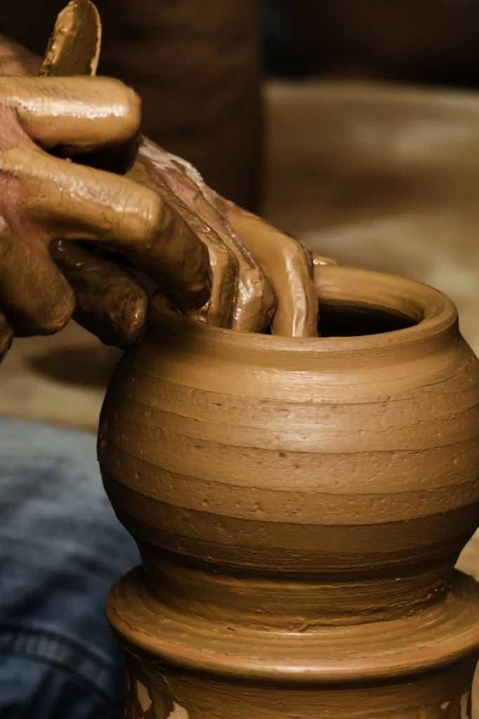Hands shaping clay on a pottery wheel, creating a vase.