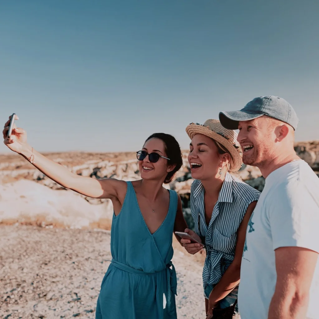 Three friends taking a selfie outdoors on a sunny day.