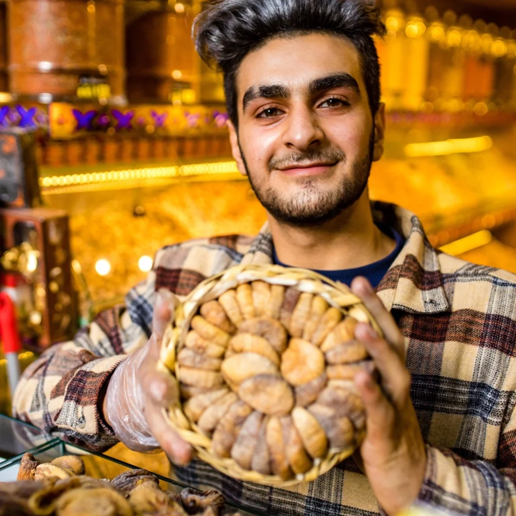 Turkish vendor holding a basket of dried figs in a market.
