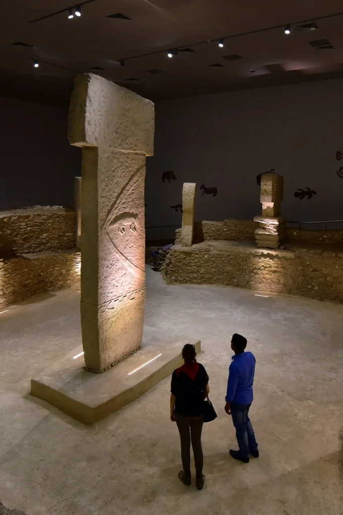 Visitors exploring Göbekli Tepe archaeological site with ancient stone pillars.