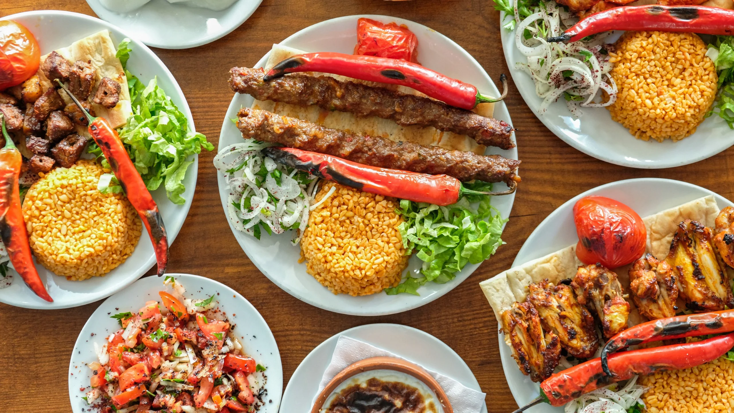 Assorted Turkish dishes with lahmacun, kebabs, and bulgur.