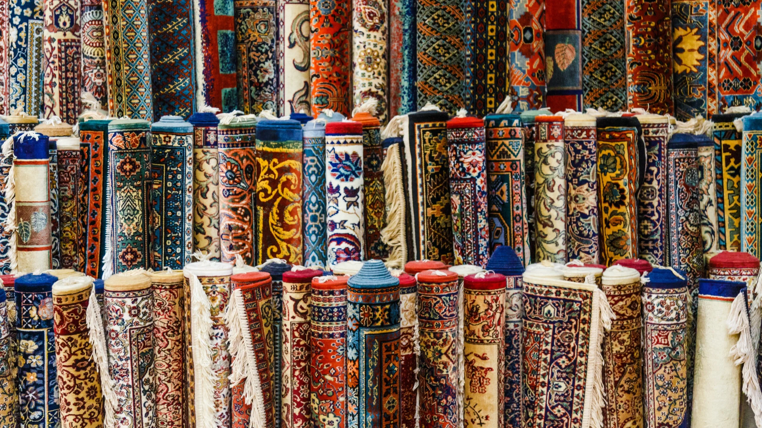 Colorful rolled carpets with intricate patterns on display.