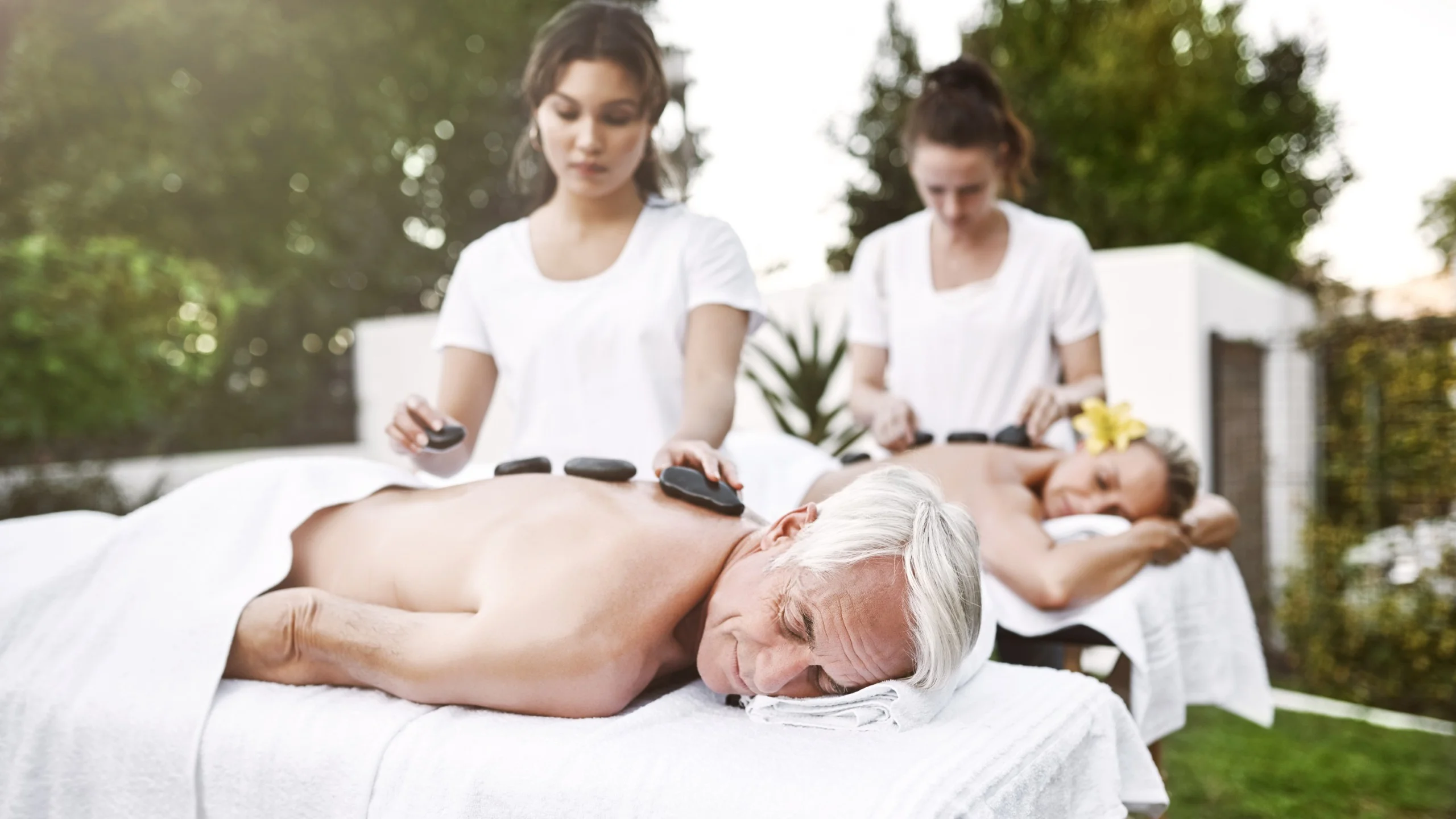 Middle-aged couple enjoying outdoor hot stone massage.
