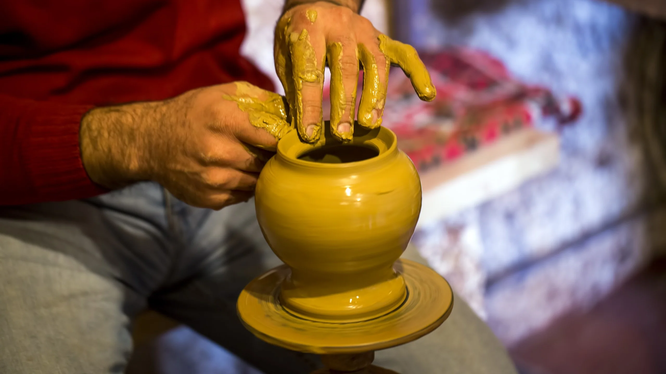 Potter shaping a clay bowl on a pottery wheel.
